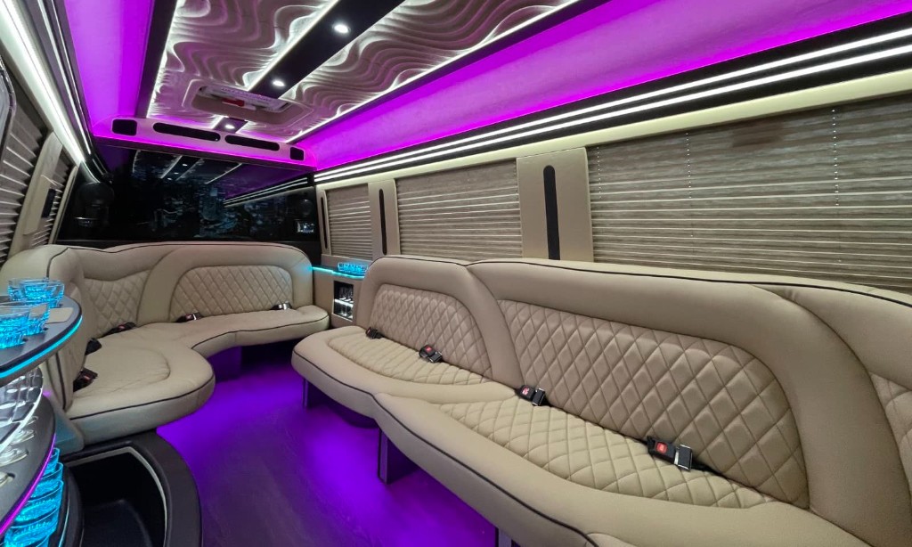 Party bus interior with purple lighting, quilted seating, and onboard bar